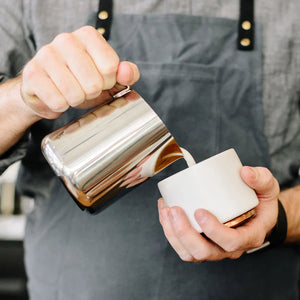 Barista ρίχνει γάλα από γυαλιστερή κανάτα από ανοξείδωτο ατσάλι, μέρος των Espresso Αξεσουάρ και Κανάτα Γάλακτος, όλα για τον καφέ.
